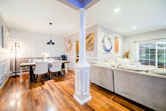 living room featuring hardwood / wood-style floors, crown molding, and decorative columns