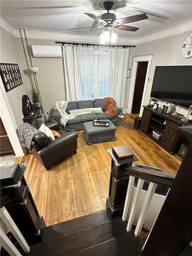 living room with ceiling fan, wood-type flooring, crown molding, and a wall unit AC