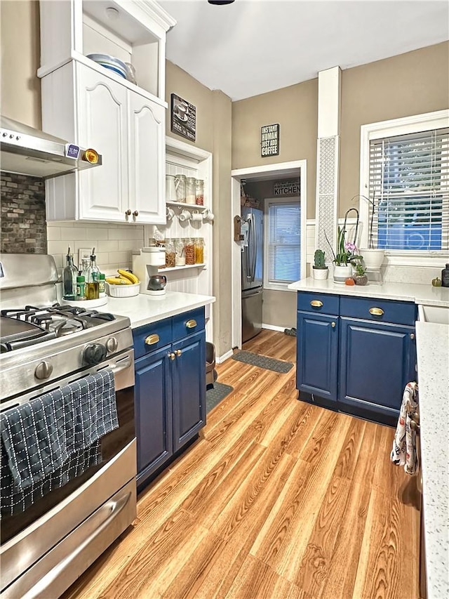 kitchen featuring light wood-type flooring, stainless steel appliances, blue cabinets, white cabinets, and range hood