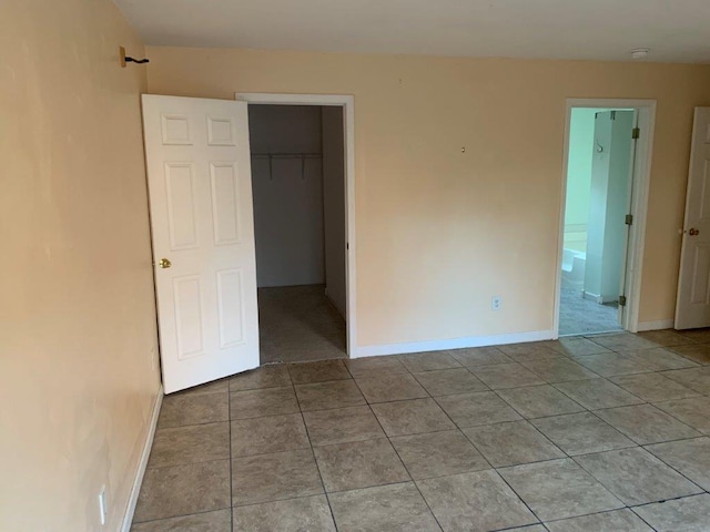 unfurnished bedroom featuring light tile patterned floors, a walk in closet, and a closet