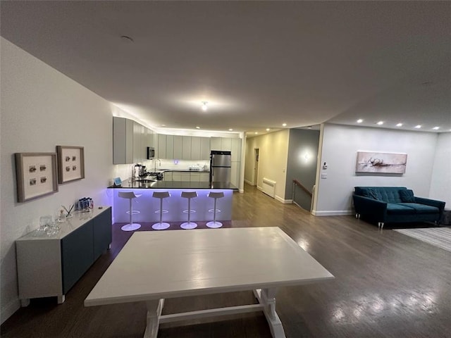 kitchen with sink, dark hardwood / wood-style floors, kitchen peninsula, white cabinets, and appliances with stainless steel finishes