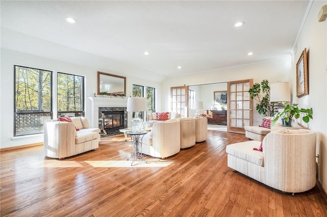 living room with crown molding, french doors, a high end fireplace, and light wood-type flooring