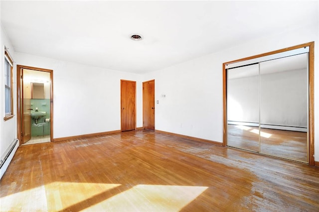 unfurnished bedroom with ensuite bathroom, sink, hardwood / wood-style flooring, a baseboard radiator, and a closet