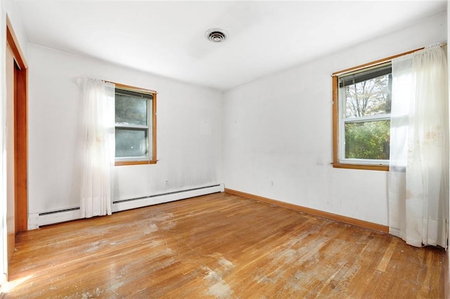 empty room featuring light wood-type flooring and a baseboard heating unit