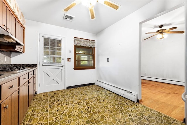 kitchen with stainless steel gas stovetop, light wood-type flooring, and baseboard heating