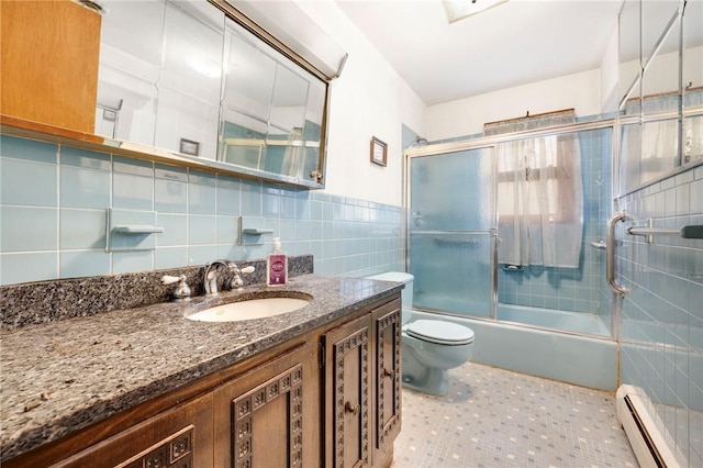 full bathroom with vanity, bath / shower combo with glass door, toilet, tile walls, and a baseboard radiator