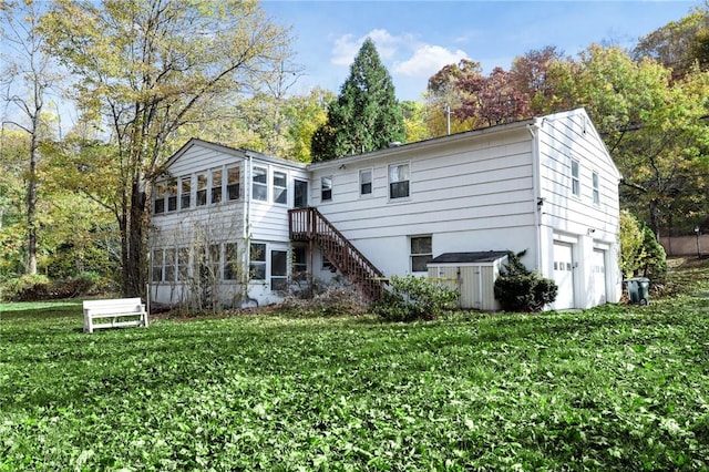 rear view of property featuring a yard, a garage, and a sunroom