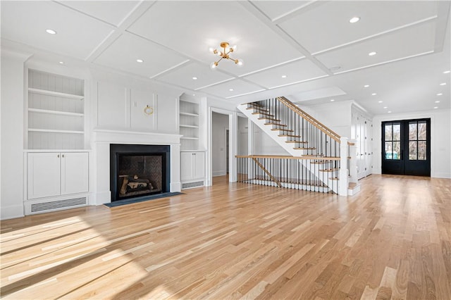 unfurnished living room with built in shelves, french doors, coffered ceiling, and light hardwood / wood-style flooring