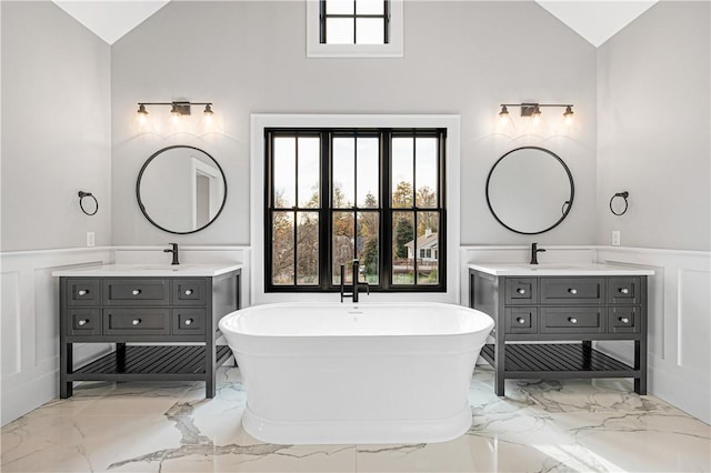 bathroom featuring vaulted ceiling, a washtub, and vanity