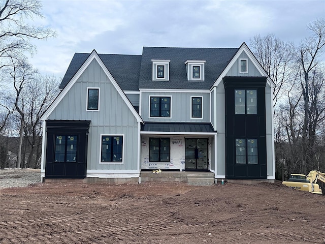 modern inspired farmhouse featuring a standing seam roof, board and batten siding, metal roof, and roof with shingles