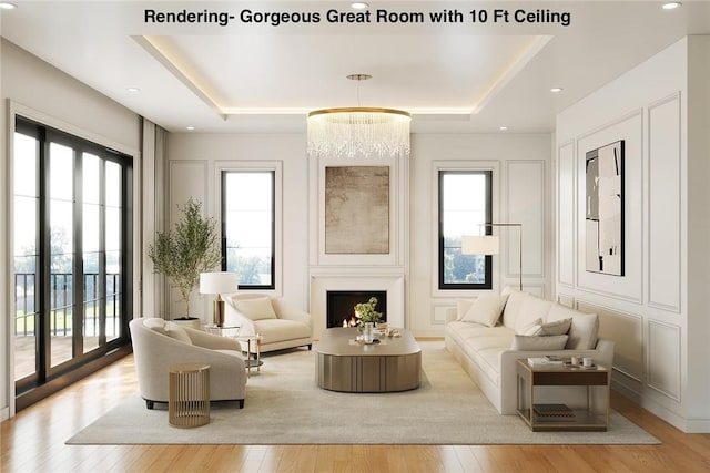 living area with a wealth of natural light, a tray ceiling, and a warm lit fireplace