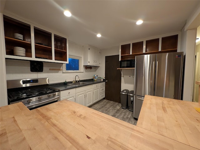 kitchen with stainless steel appliances, dark wood-type flooring, sink, white cabinets, and butcher block countertops