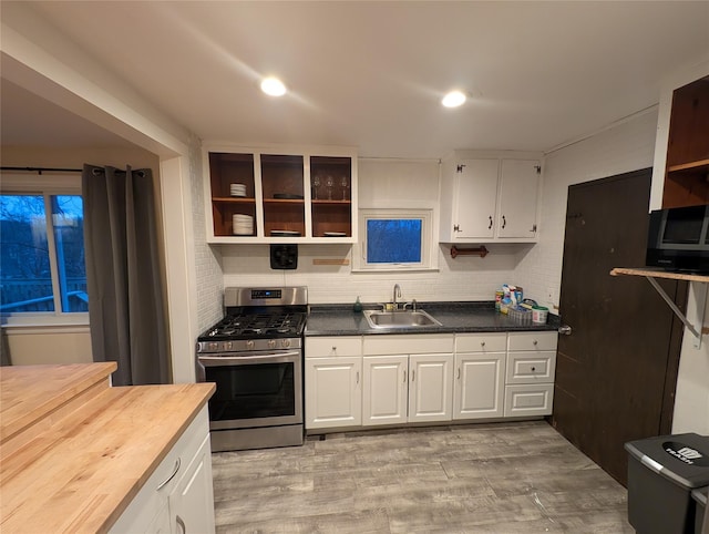 kitchen with white cabinetry, sink, stainless steel gas range, wooden counters, and light hardwood / wood-style floors