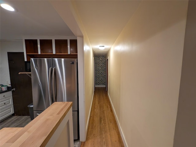 kitchen with hardwood / wood-style flooring, wood counters, and stainless steel refrigerator