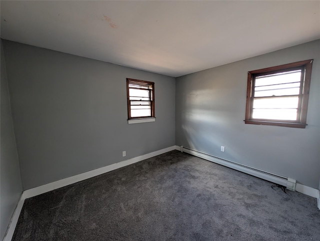 spare room with dark carpet and a baseboard heating unit