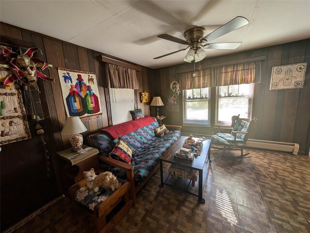 living room featuring baseboard heating, ceiling fan, and wood walls