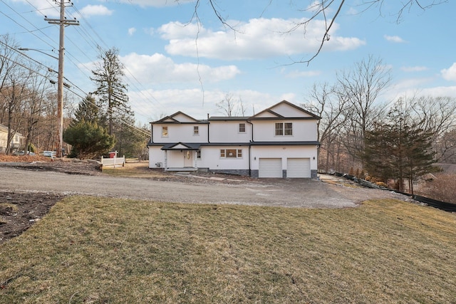 back of property with aphalt driveway, a lawn, an attached garage, and stucco siding