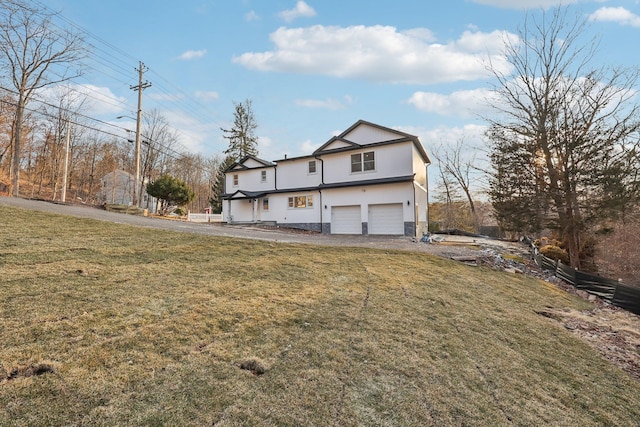 back of house featuring a garage, driveway, and a lawn