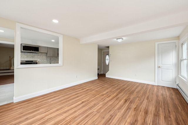 unfurnished living room with a baseboard heating unit, recessed lighting, light wood-style flooring, and baseboards