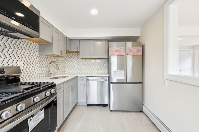 kitchen with a baseboard heating unit, stainless steel appliances, a sink, and gray cabinetry