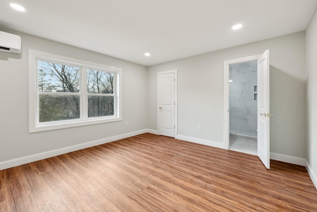 unfurnished bedroom featuring a wall mounted AC, recessed lighting, light wood-style flooring, and baseboards