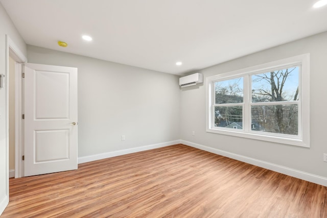 unfurnished room featuring light wood-type flooring, an AC wall unit, baseboards, and recessed lighting