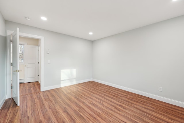 spare room featuring recessed lighting, wood finished floors, and baseboards