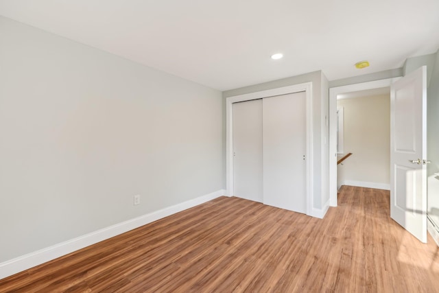 unfurnished bedroom with recessed lighting, a closet, light wood-type flooring, and baseboards