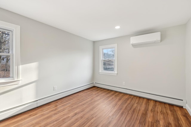 empty room with recessed lighting, a baseboard heating unit, wood finished floors, and a wall mounted air conditioner