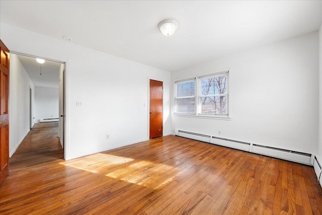 unfurnished bedroom with light wood-type flooring and a baseboard heating unit