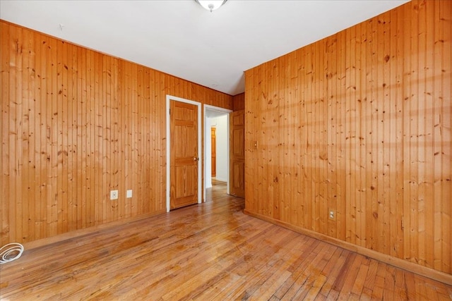 unfurnished room with hardwood / wood-style flooring and wood walls