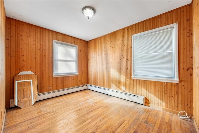 spare room featuring wood walls, a baseboard radiator, and hardwood / wood-style flooring