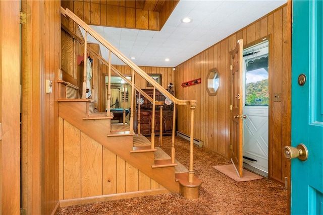 entrance foyer featuring wood walls, carpet floors, and a baseboard radiator