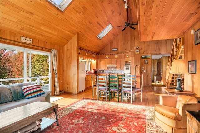 living room featuring high vaulted ceiling, light hardwood / wood-style flooring, ceiling fan, and wood walls