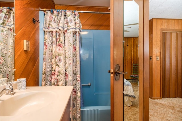 bathroom featuring vanity, shower / tub combo with curtain, and wooden walls