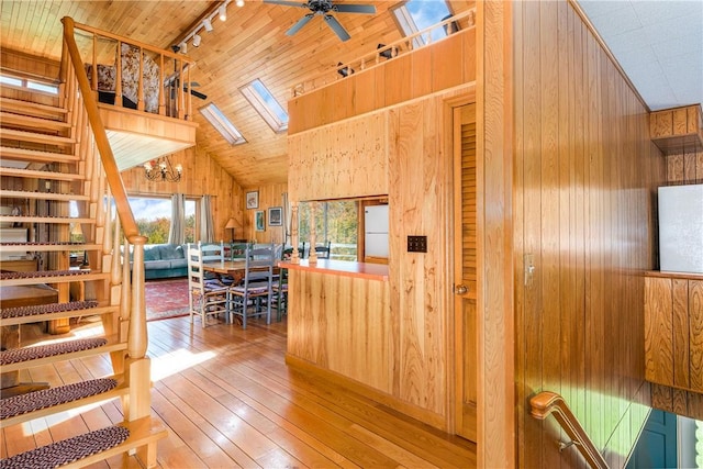 stairway featuring ceiling fan, wooden walls, wood-type flooring, high vaulted ceiling, and wooden ceiling