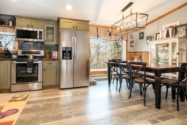 kitchen with hanging light fixtures, stainless steel appliances, a baseboard heating unit, light hardwood / wood-style floors, and green cabinetry