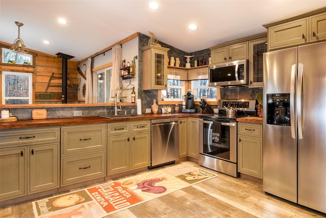 kitchen with wooden walls, sink, plenty of natural light, and appliances with stainless steel finishes