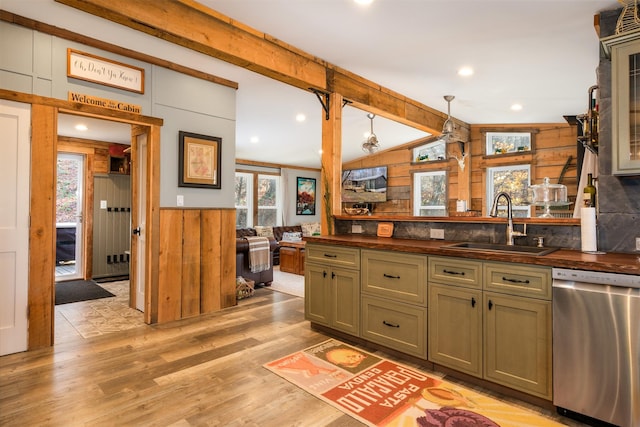 kitchen with stainless steel dishwasher, sink, pendant lighting, lofted ceiling with beams, and light hardwood / wood-style floors