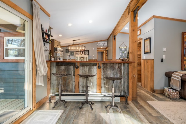 bar featuring hanging light fixtures, an inviting chandelier, crown molding, hardwood / wood-style floors, and lofted ceiling