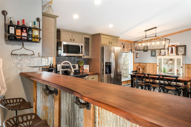 kitchen with appliances with stainless steel finishes, backsplash, a kitchen breakfast bar, decorative light fixtures, and butcher block countertops