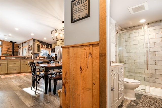 bathroom with walk in shower, vanity, hardwood / wood-style floors, toilet, and wood walls