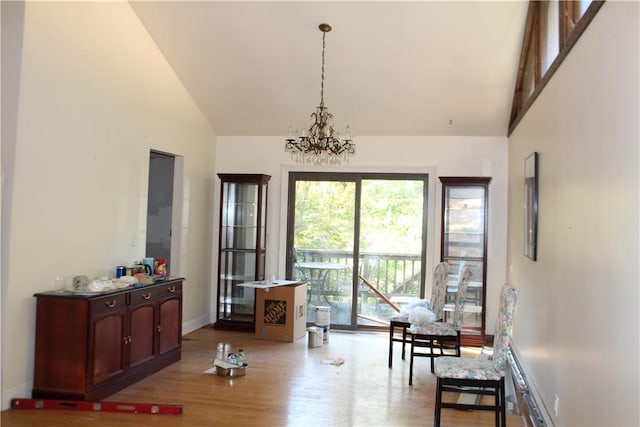 living area featuring baseboards, high vaulted ceiling, light wood-style flooring, and an inviting chandelier