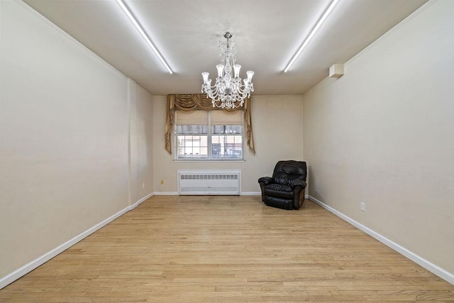 unfurnished room with light wood-type flooring, radiator, and a notable chandelier