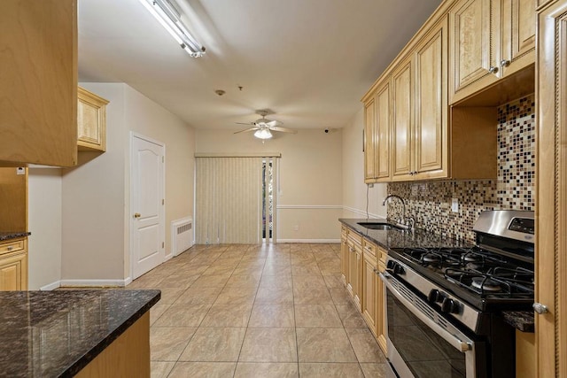 kitchen with gas range, radiator, sink, tasteful backsplash, and dark stone countertops