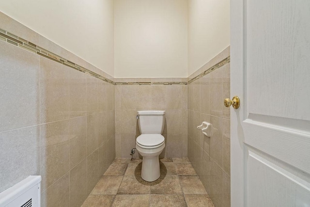 bathroom with toilet and tile walls