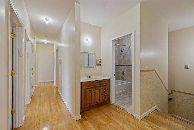 corridor with light hardwood / wood-style floors and sink