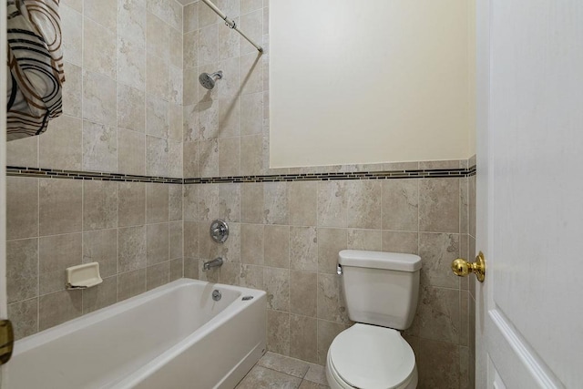 bathroom featuring tile patterned floors, toilet, tile walls, and tiled shower / bath