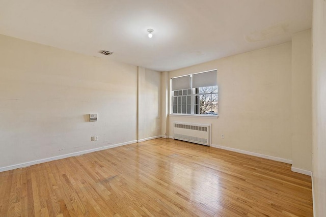 empty room featuring radiator and light hardwood / wood-style flooring