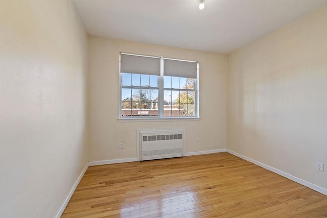 empty room with light hardwood / wood-style flooring and radiator